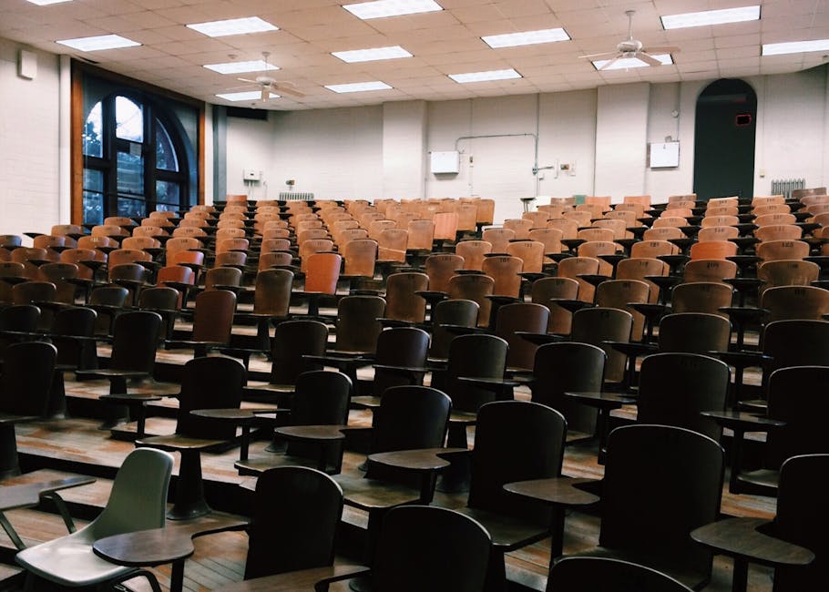 Empty university lecture hall with wooden chairs and large windows